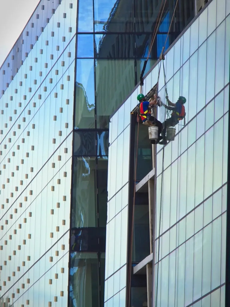 Professional window cleaner performing commercial glass cleaning on a high-rise building